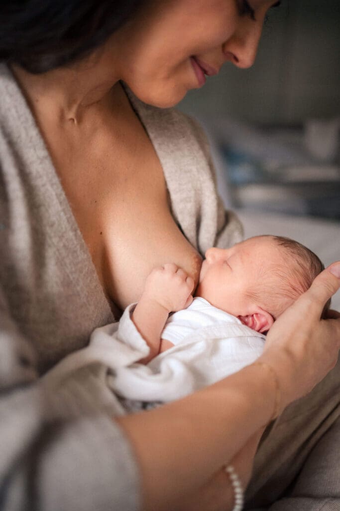 Newborn nurses while the mother looks down smiling at her baby