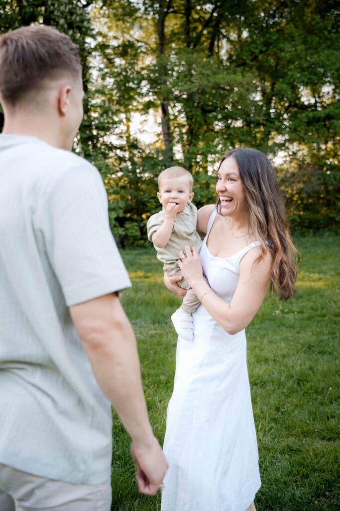 Happy couple and baby share joyful outdoor moments together in a green park setting during golden hour.