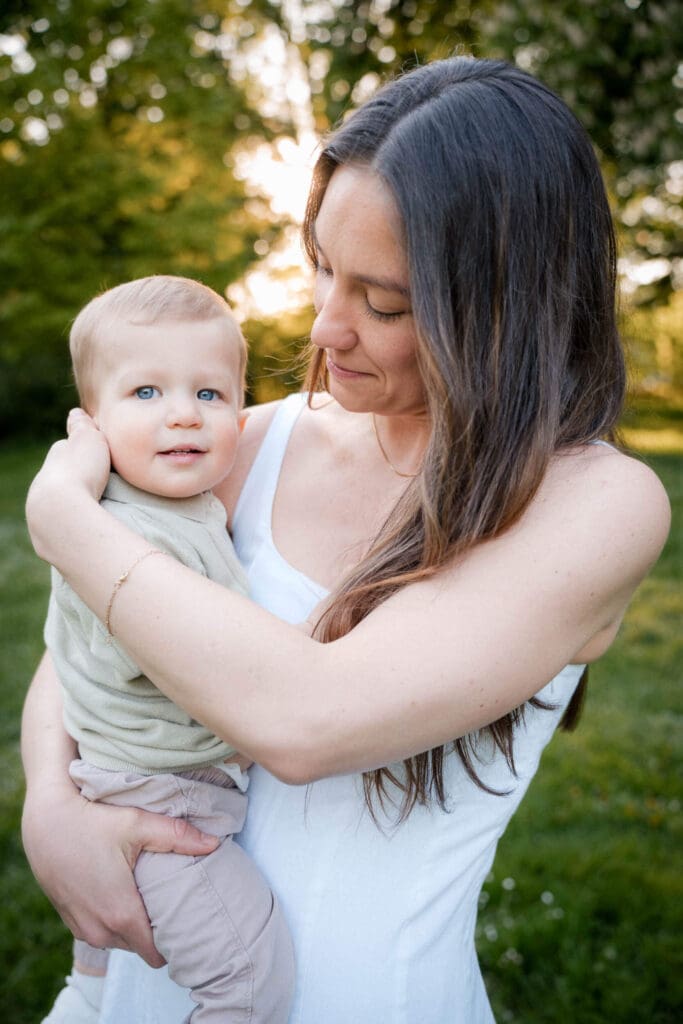 Mom cuddling baby in light, neutral-toned outfit during summer family photoshoot in Munich.