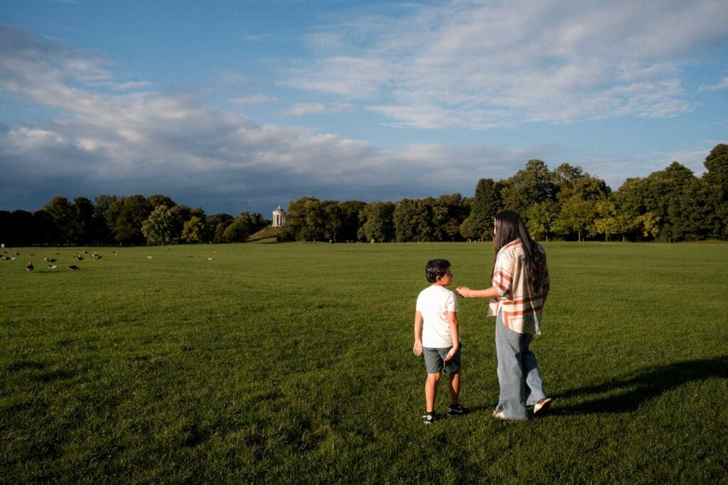 Mom and son enjoy moment in the Englischer Garten in the open meadow at sunset.