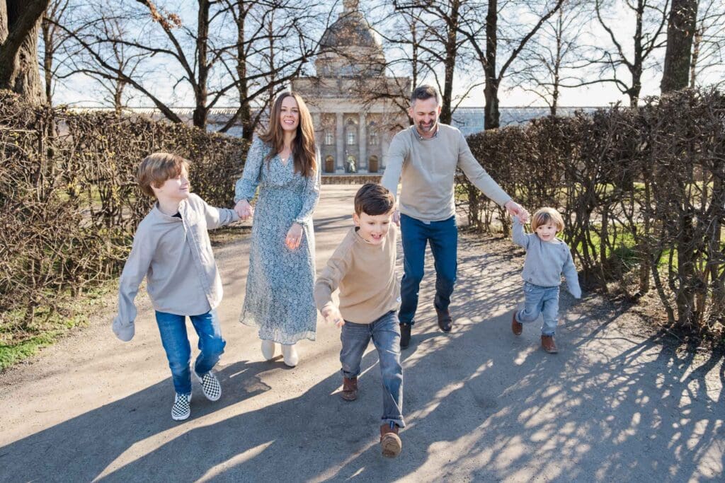 Three young boys pull their parents along during a family photoshoot in the Hofgarten.