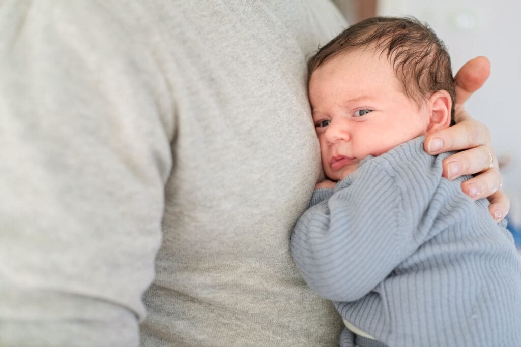 newborn baby snuggles against dad's chest during newborn photos at home in Munich