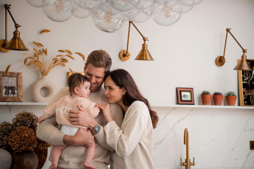 A family shares an intimate moment together in a cozy room with gold light fixtures.