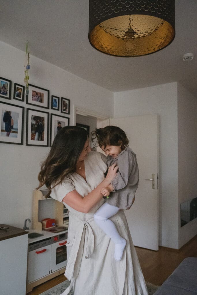 Mother holding toddler daughter dancing during natural lifestyle family session in Munich