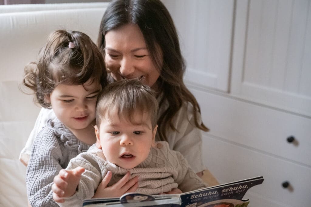 Mother reading to two toddlers on her lap during candid lifestyle photography session