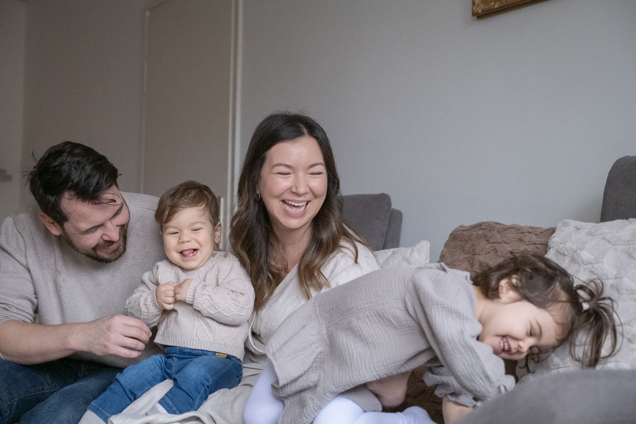 Family of four relaxing together on bed during lifestyle photography session in Munich