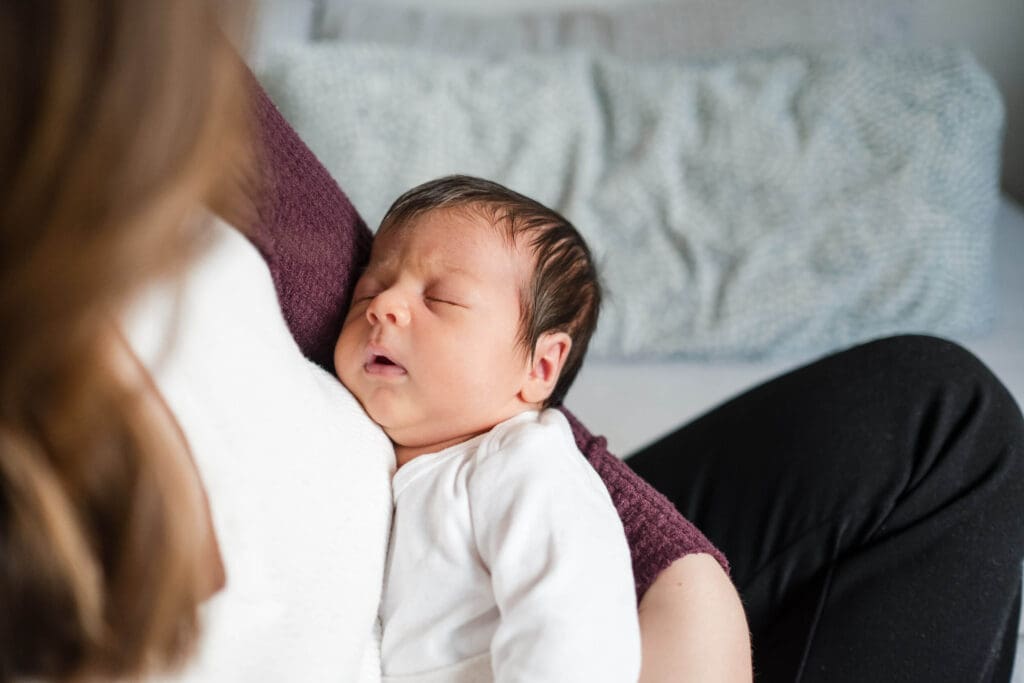Baby takes a quick nap nestled in her mother’s arm during her baby photoshoot at home.