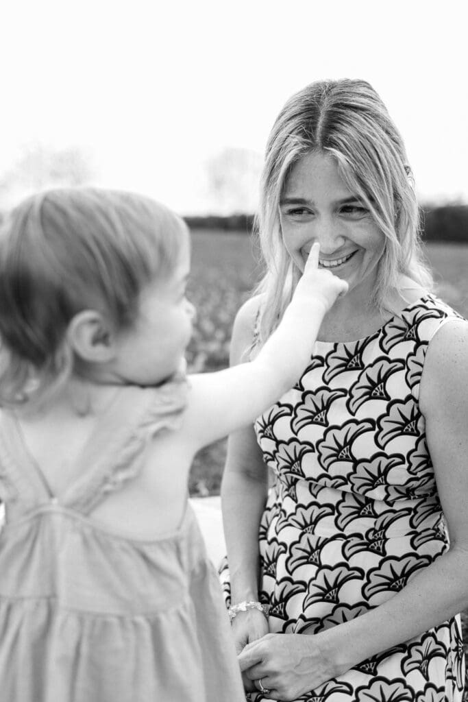Toddler reaches out to poke mom's nose