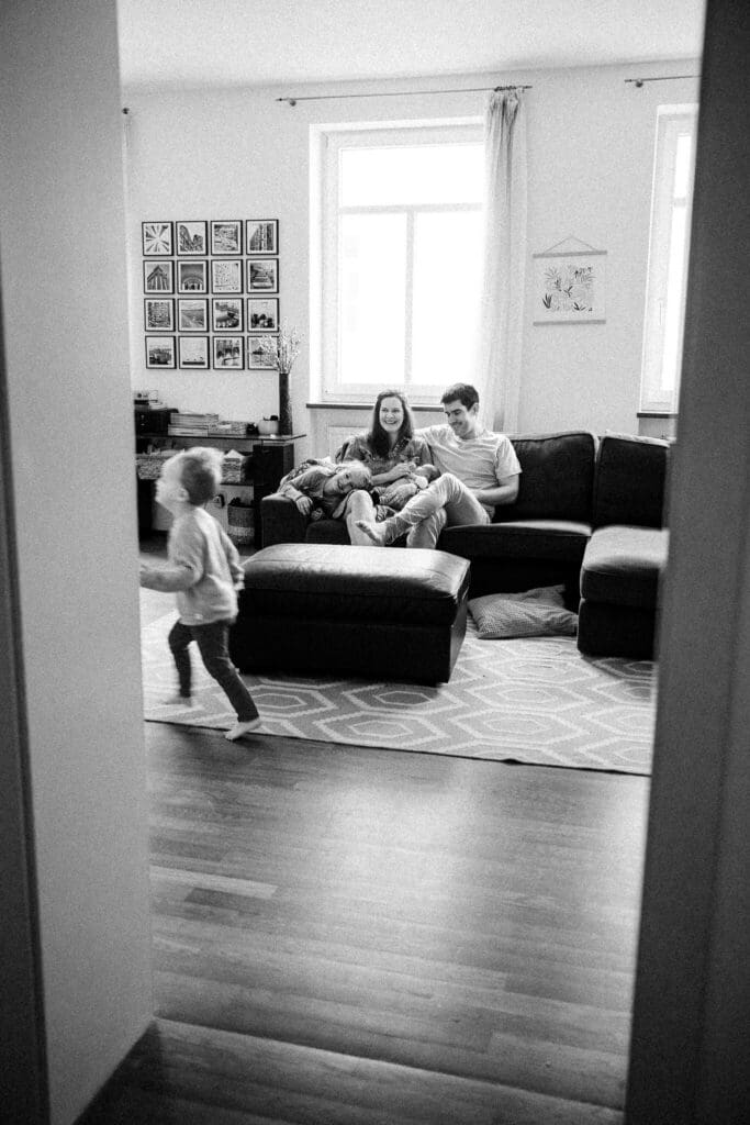 Black and white snapshot of silly family life during a candid in-home newborn photoshoot in Munich