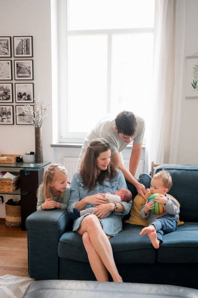 Family of five sits on couch at home during an in-home newborn photography session