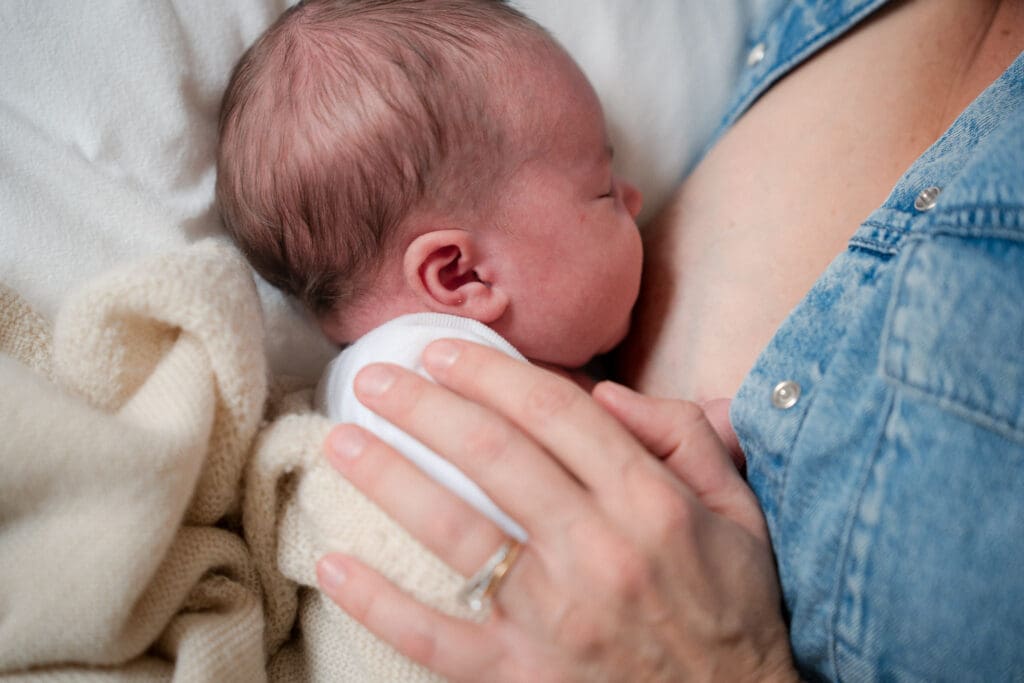 Mother nursing newborn baby during in-home photoshoot