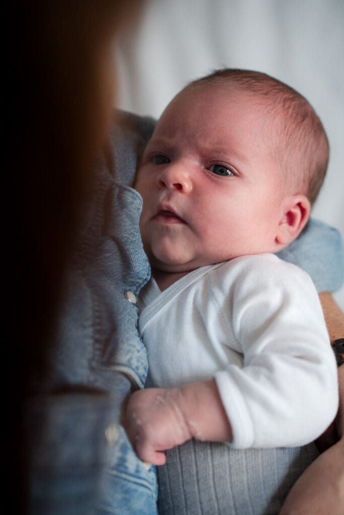 Alert newborn baby being held during lifestyle photography session at home