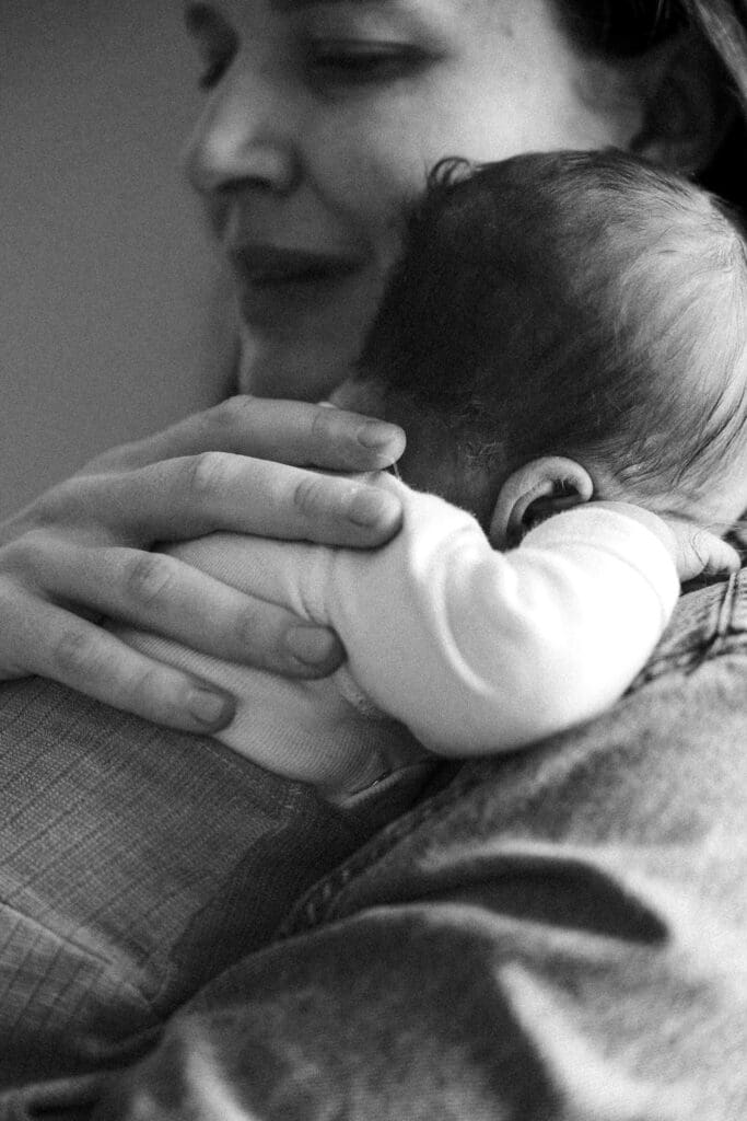 Mom holding newborn baby in intimate black and white lifestyle portrait
