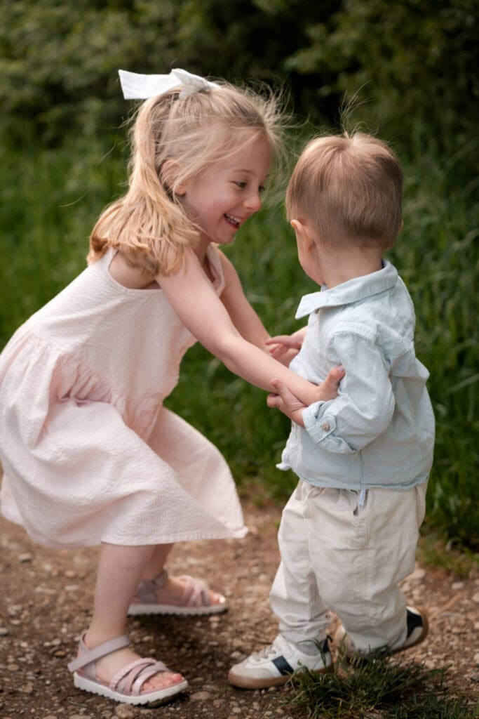 Big sister bending down laughing at her baby brother
