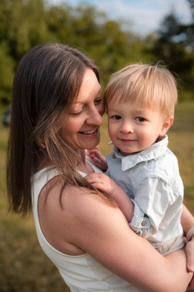 Mom holding her toddler son close in golden hour light