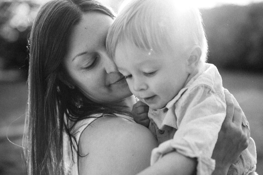 Mom holding her baby boy cheek to cheek in a quiet tender moment during their family photoshoot