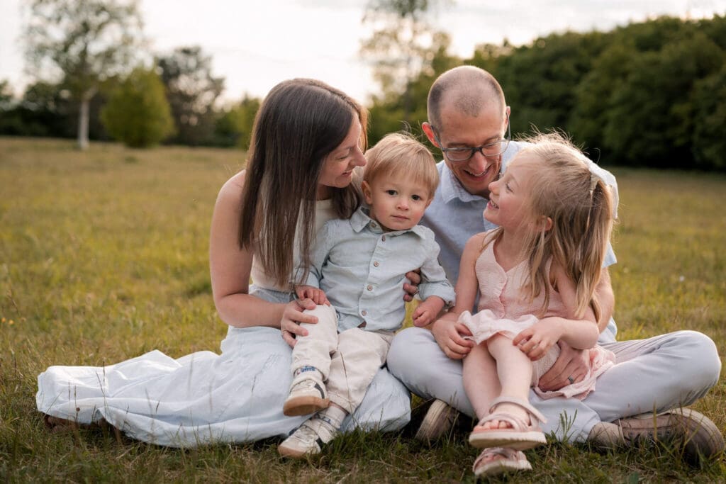 Munich expat Family of four sitting together laughing in a meadow