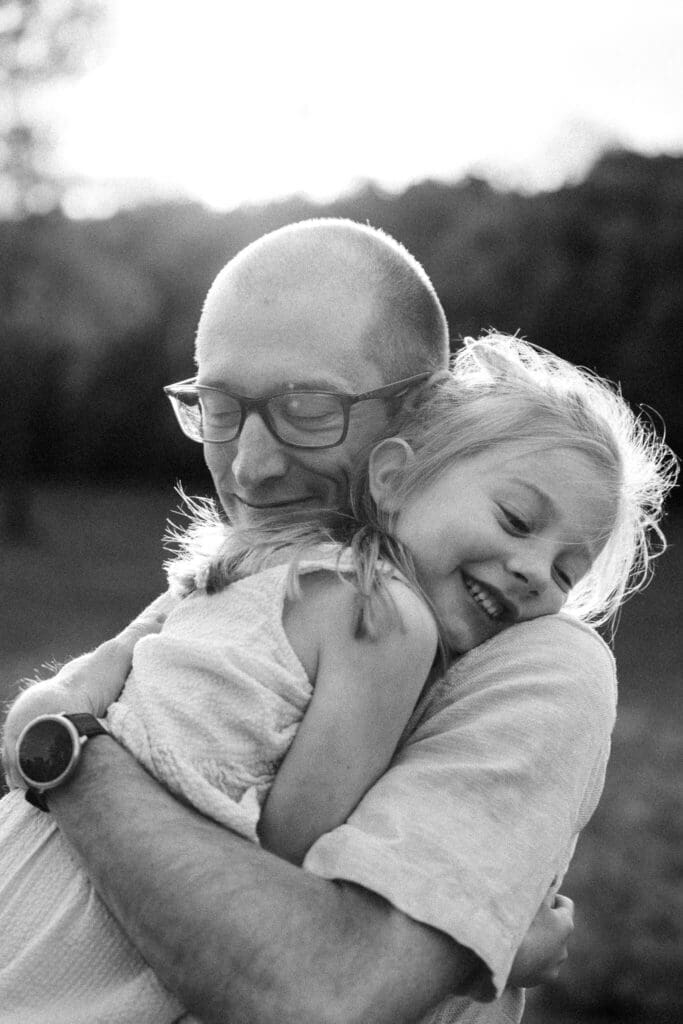 Dad hugging his daughter tight as she laughs into his chest