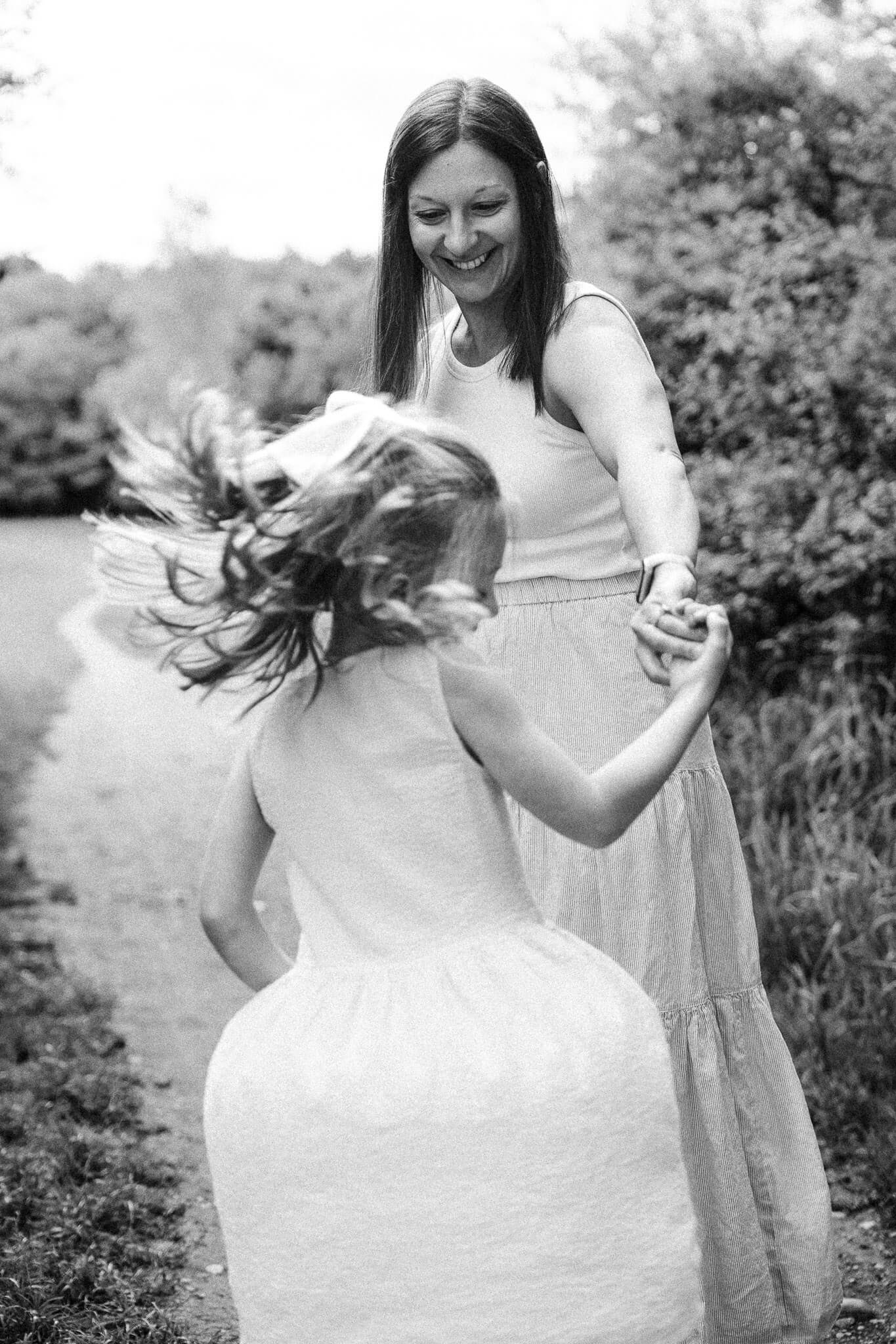 Mum spinning her daughter on a path as they both laugh during their family photo session in Riemerpark