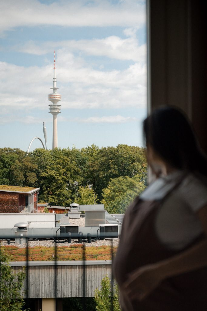 Pregnant woman looking out her window toward the Olympiaturm in Munich