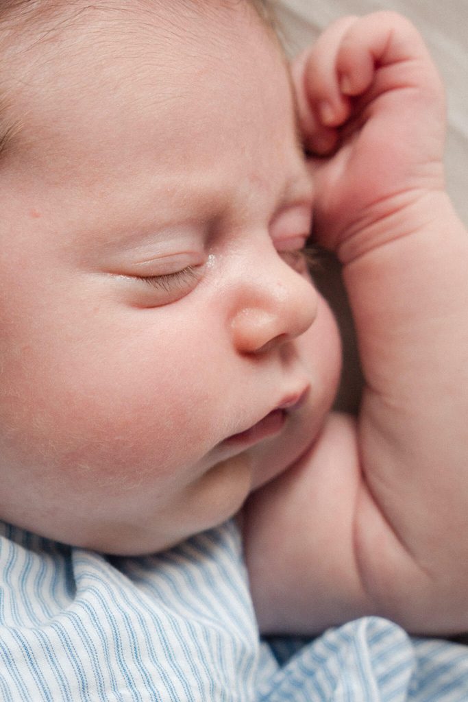 Close-up of a sleeping newborn’s face and tiny hand